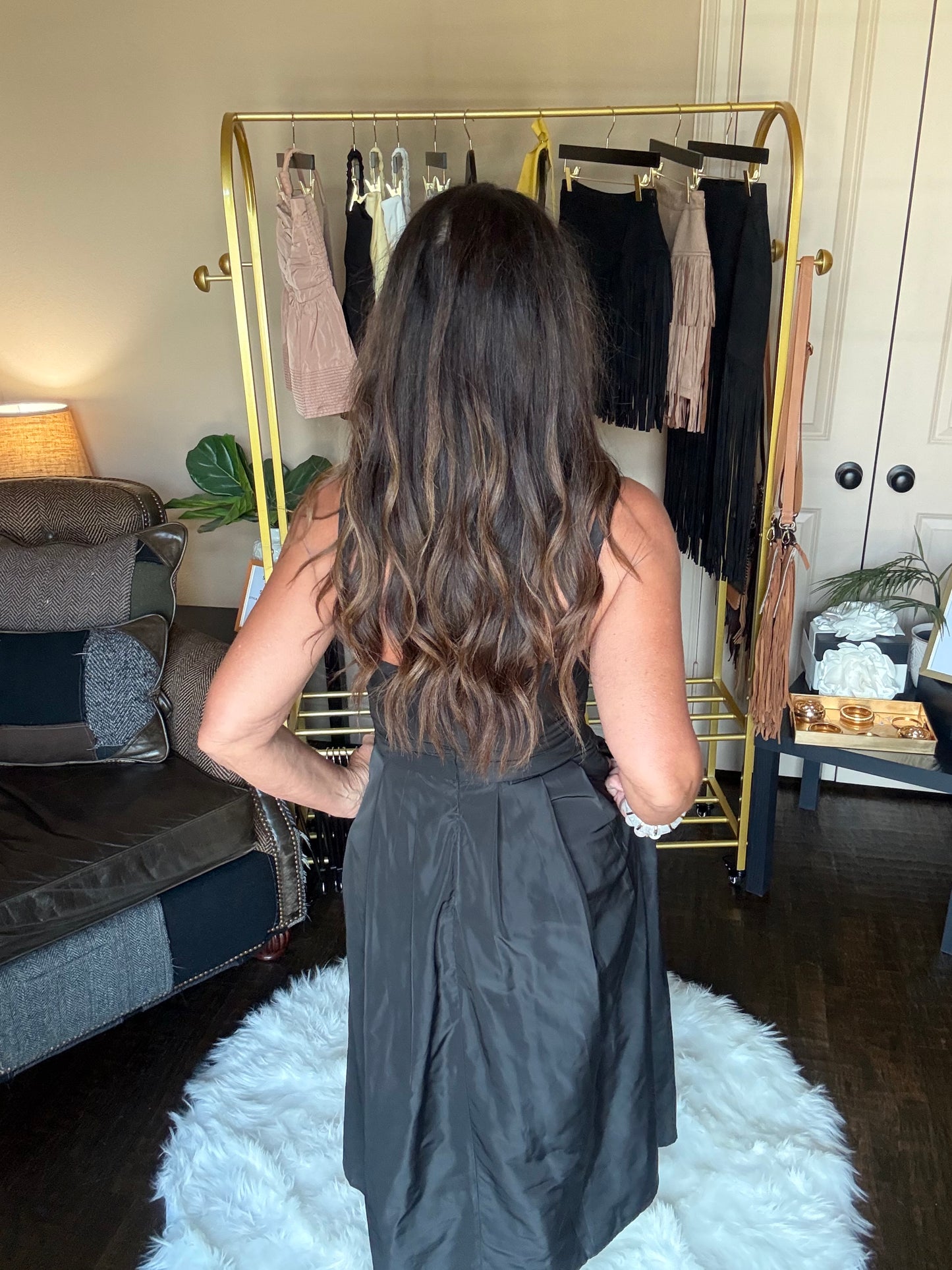 Woman in a black dress standing in front of a mirror at a boutique.