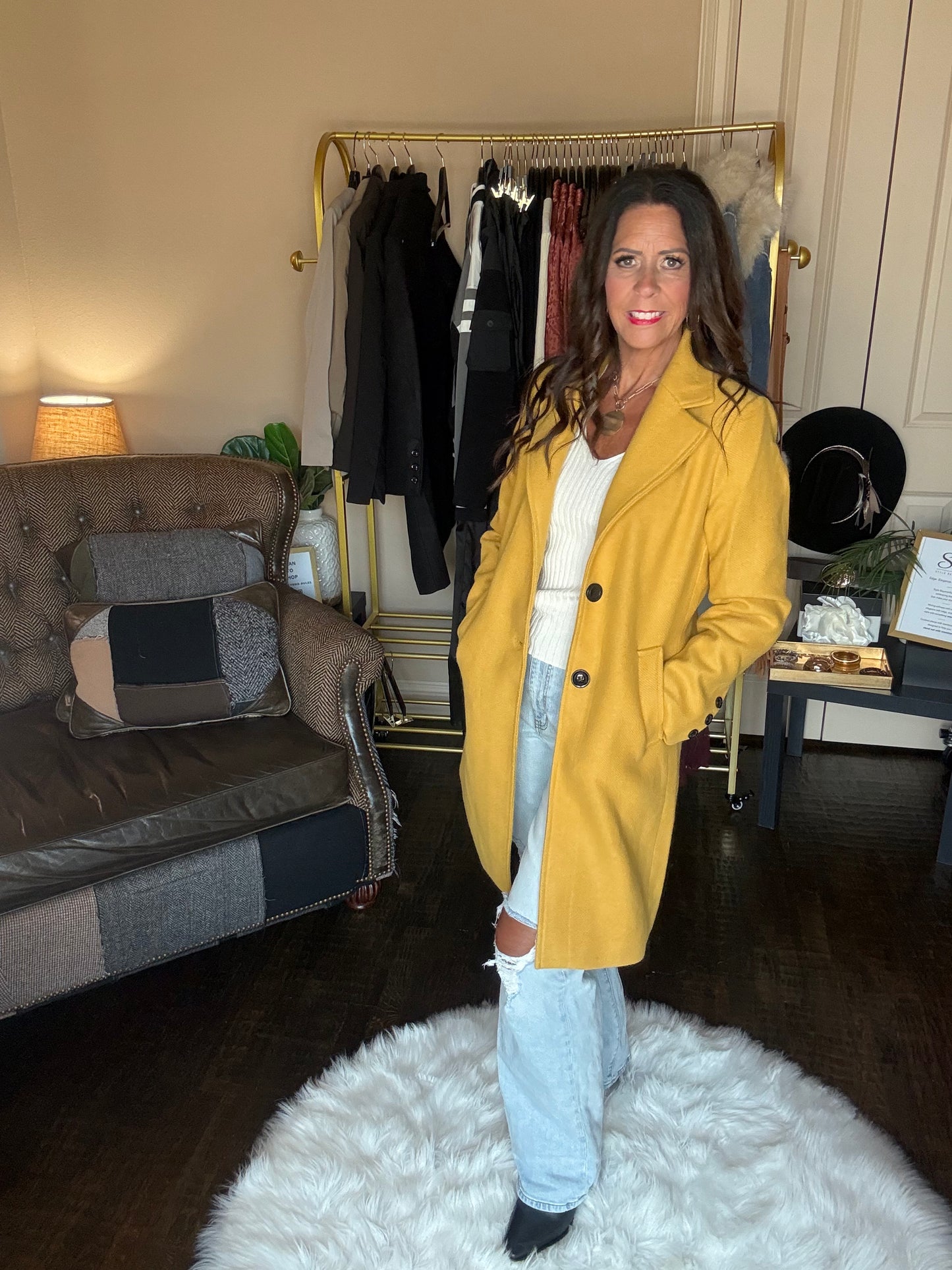 Model is wearing a yellow coat and jeans.