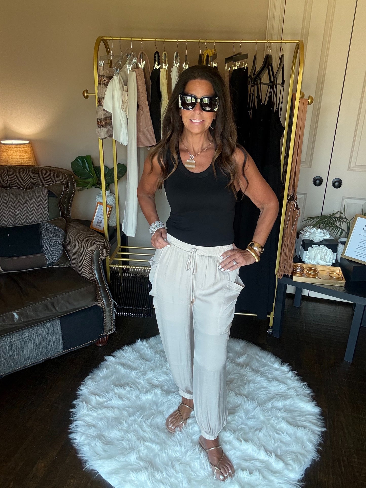 Woman posing in a room with a clothing rack and furniture.