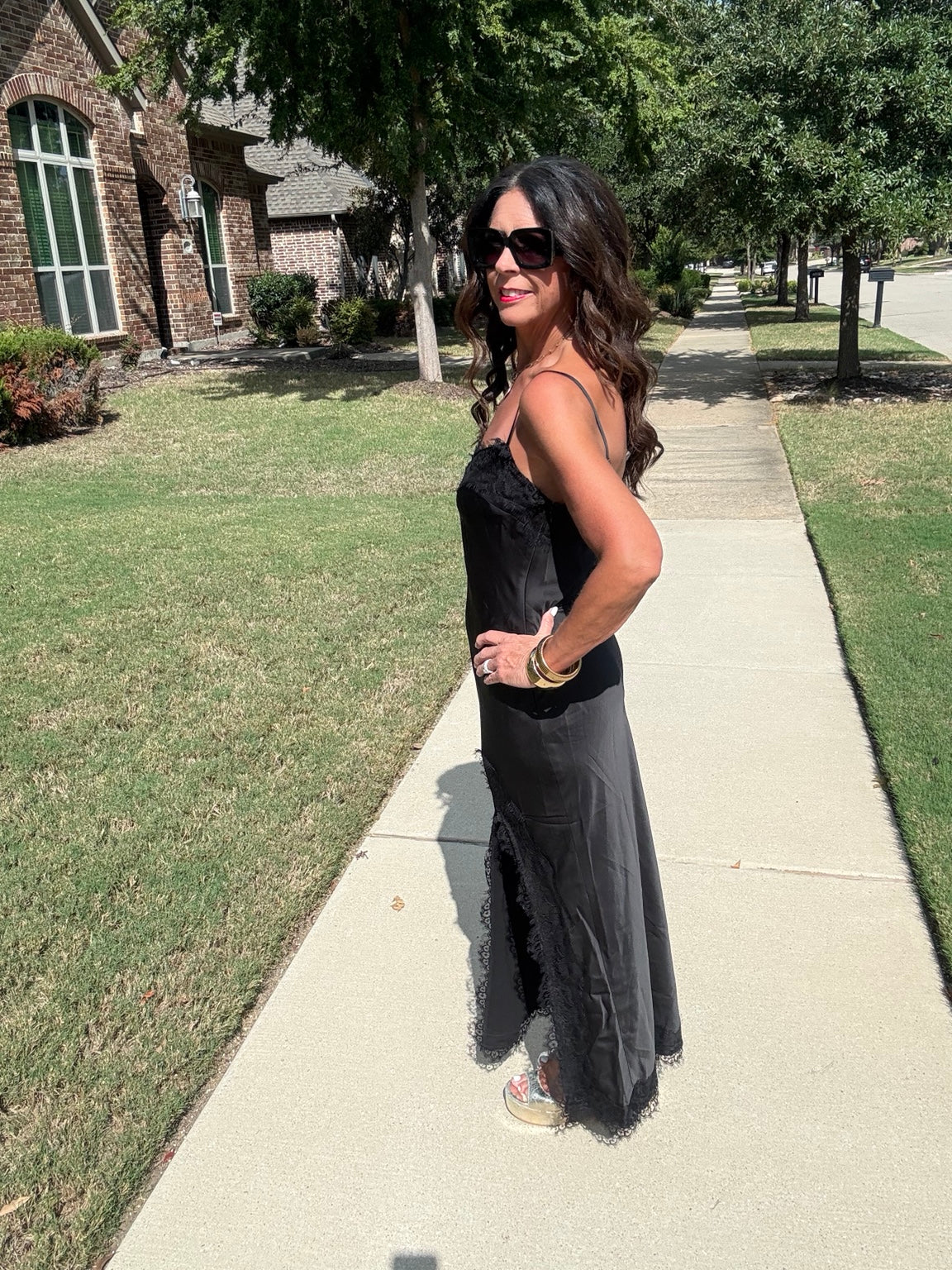 Black satin lace trim slip maxi dress in a side pose, showing spaghetti straps and flowing skirt.
