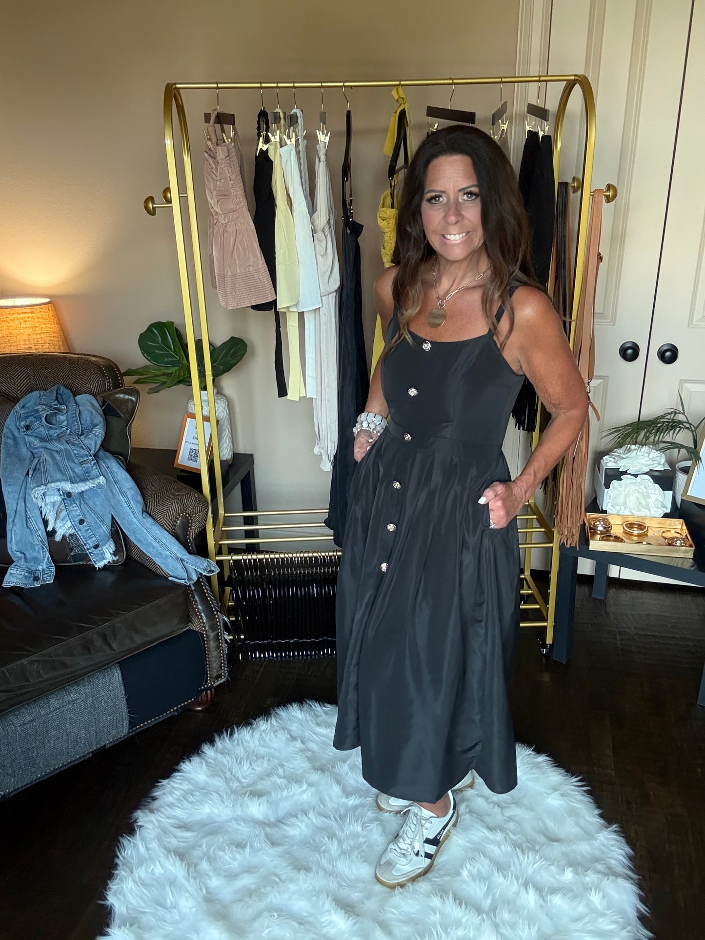Woman in a black dress standing in front of a mirror at a boutique.