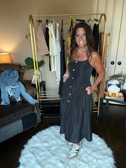 Woman in a black dress standing in front of a mirror at a boutique.