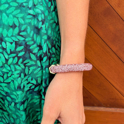 Close-up of a pink Holst + Lee Sparkle Bracelet worn on the wrist beside a green patterned dress.
