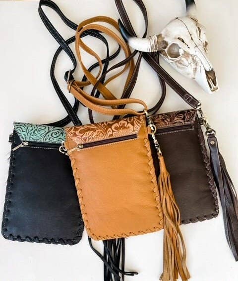 Three leather handbags in black, brown, and dark brown with decorative straps on a white background.