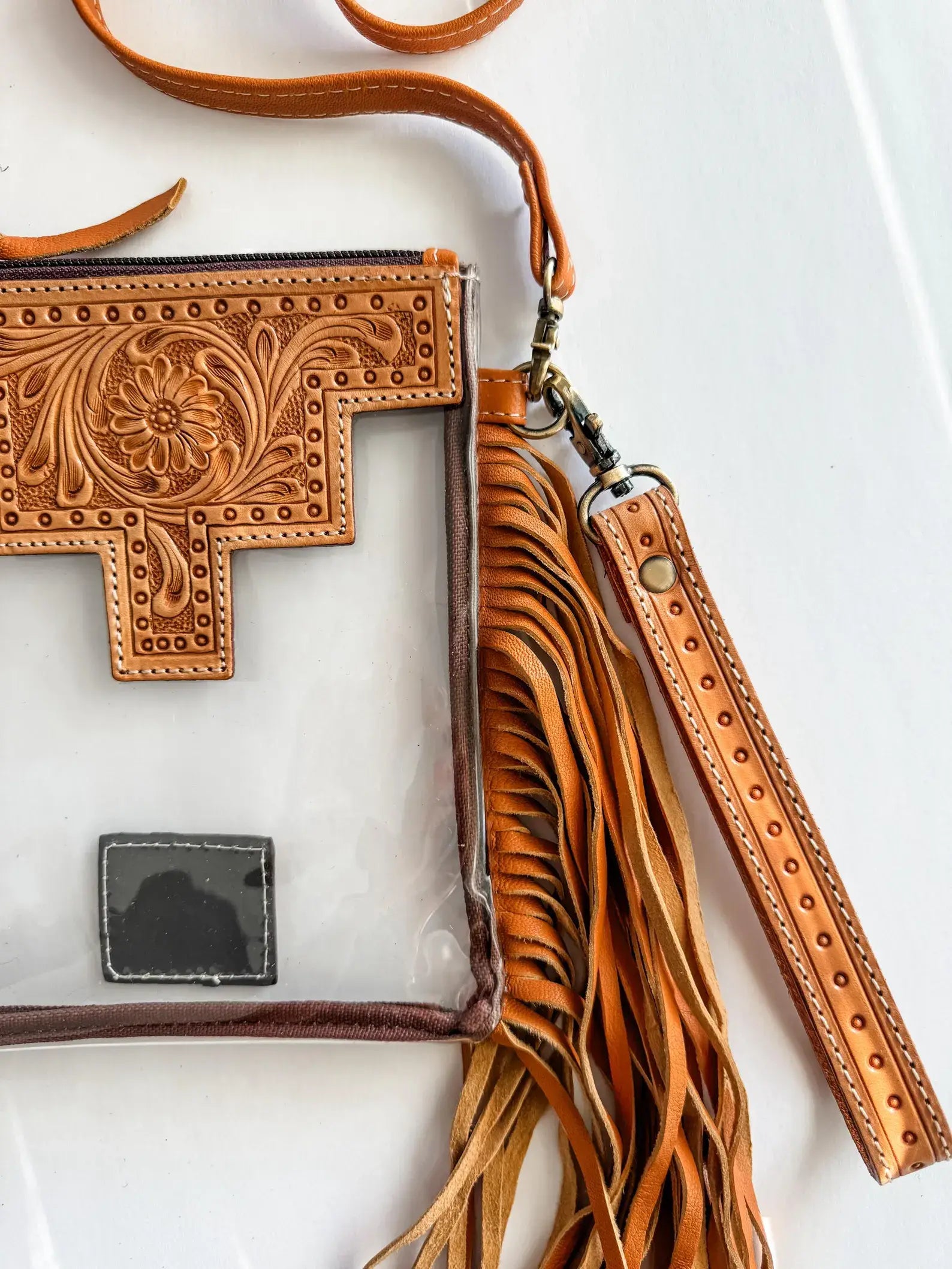 Brown leather crossbody bag with intricate designs on a white background