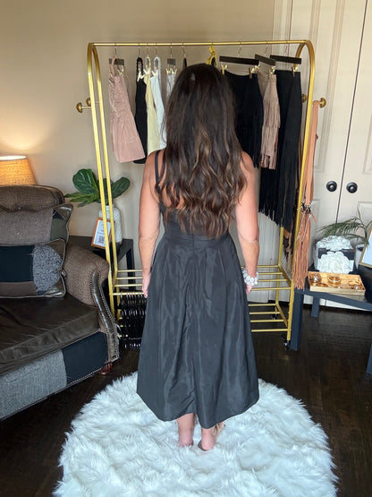 Woman in a black dress standing in front of a mirror at a boutique.