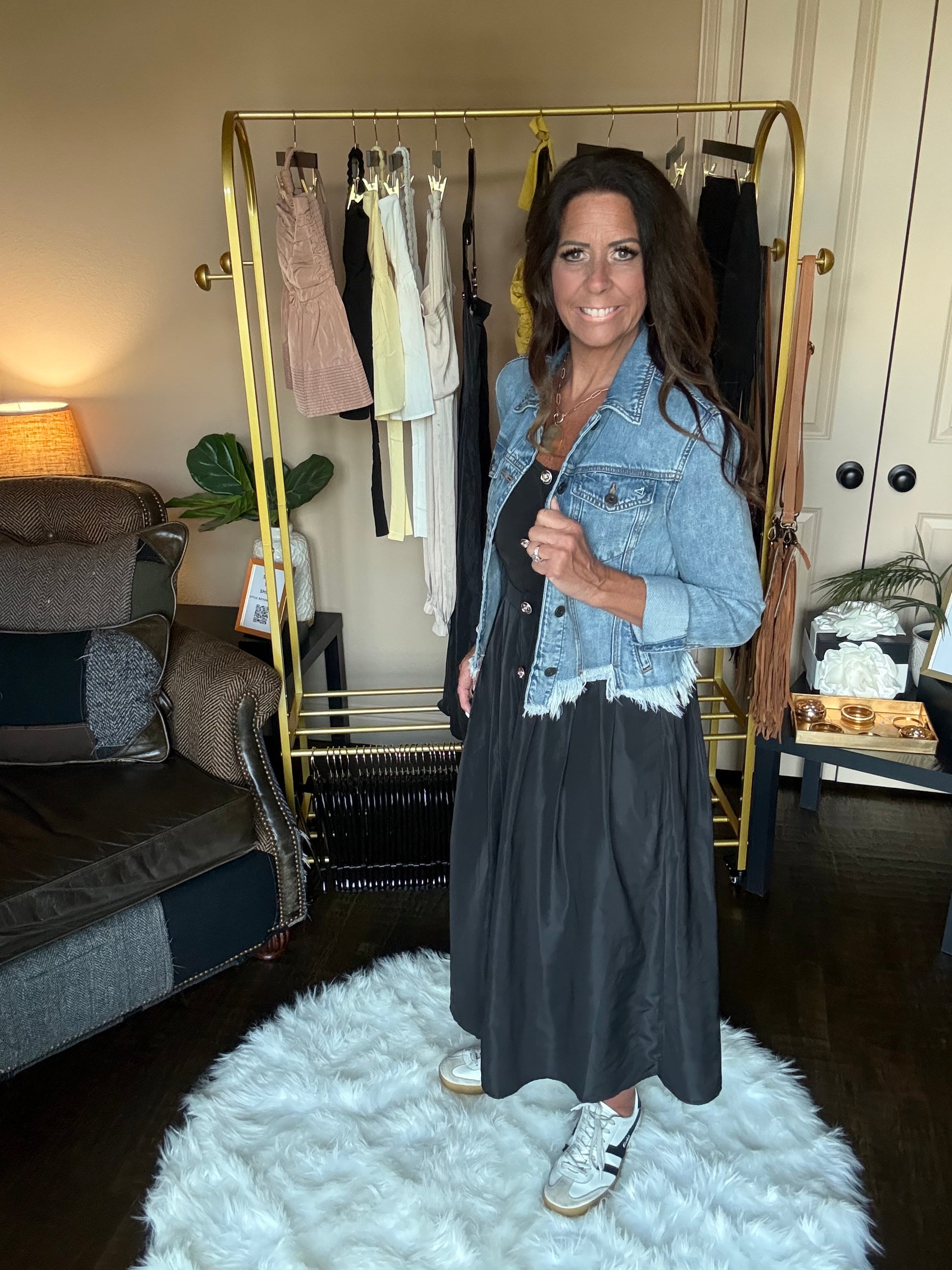 Woman in a black dress standing in front of a mirror at a boutique.
