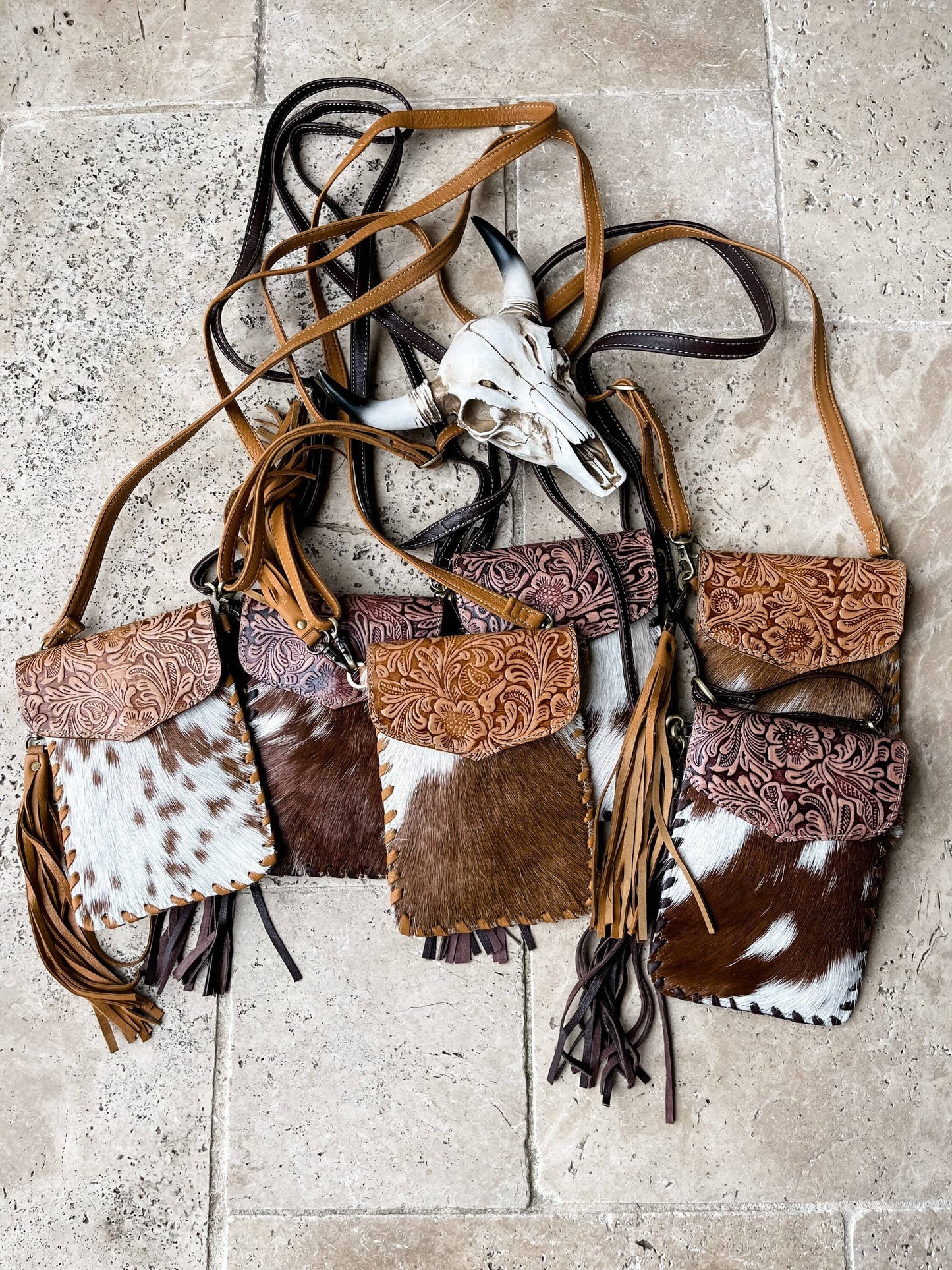 Collection of leather bags with tassels and a skull on a stone surface
