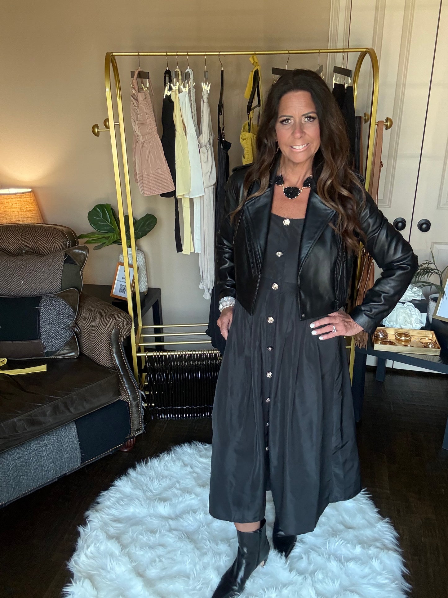 Woman in a black dress standing in front of a mirror at a boutique.