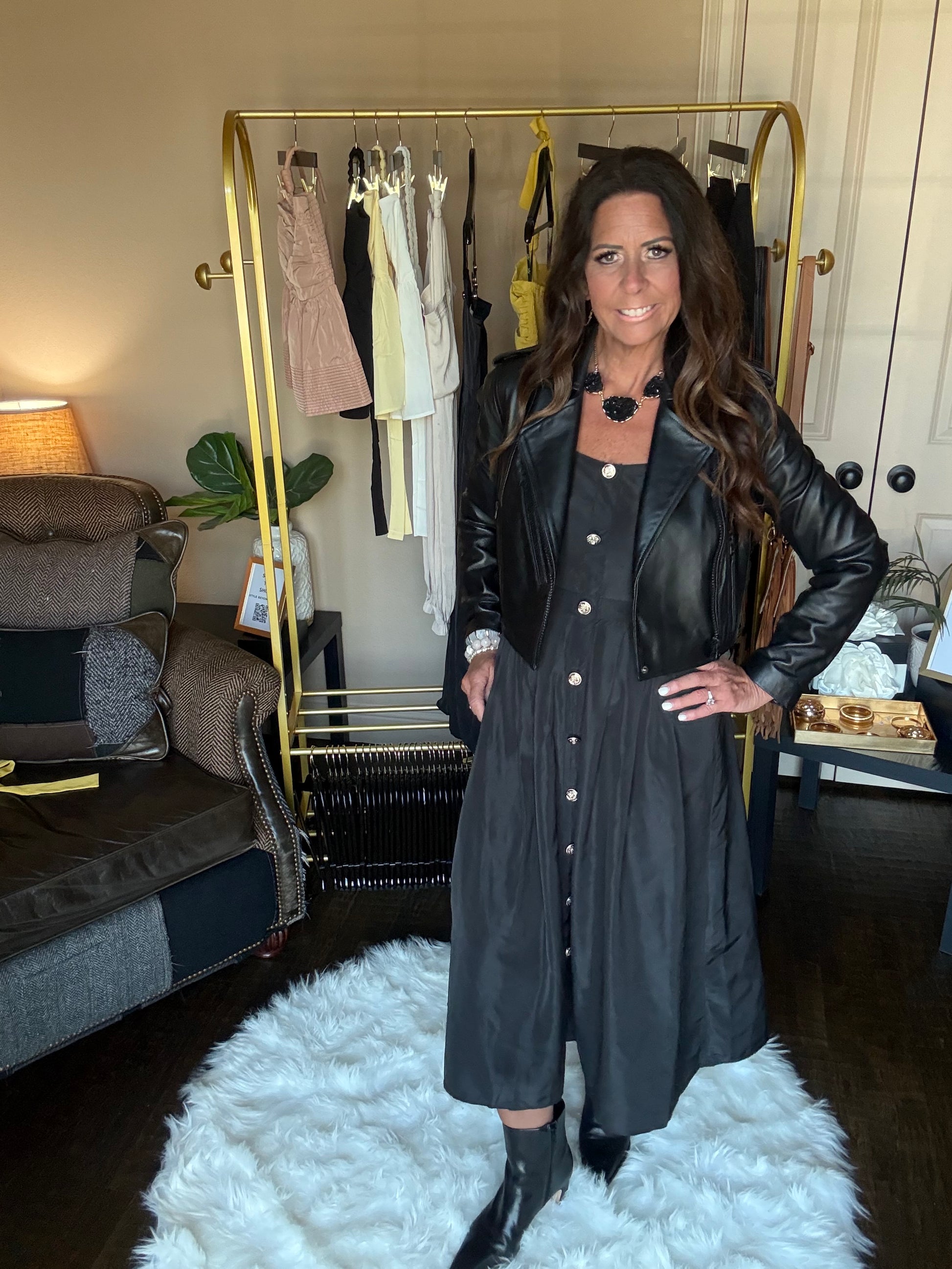 Woman in a black dress standing in front of a mirror at a boutique.