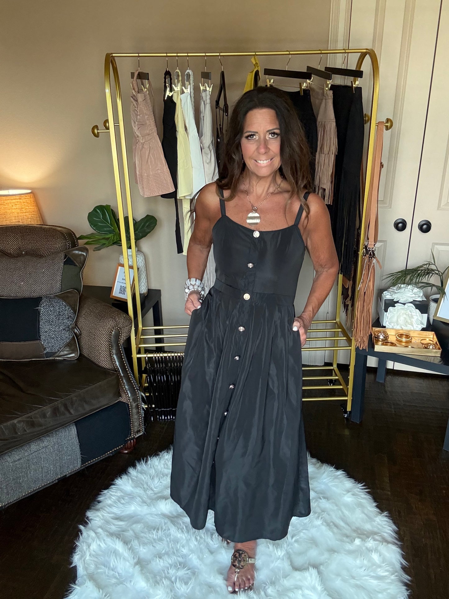 Woman in a black dress standing in front of a mirror at a boutique.