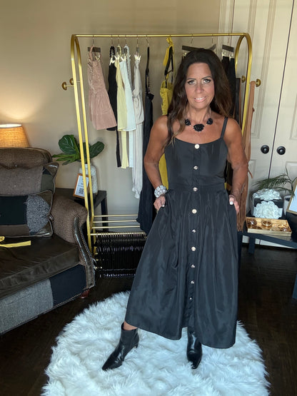 Woman in a black dress standing in front of a mirror at a boutique.