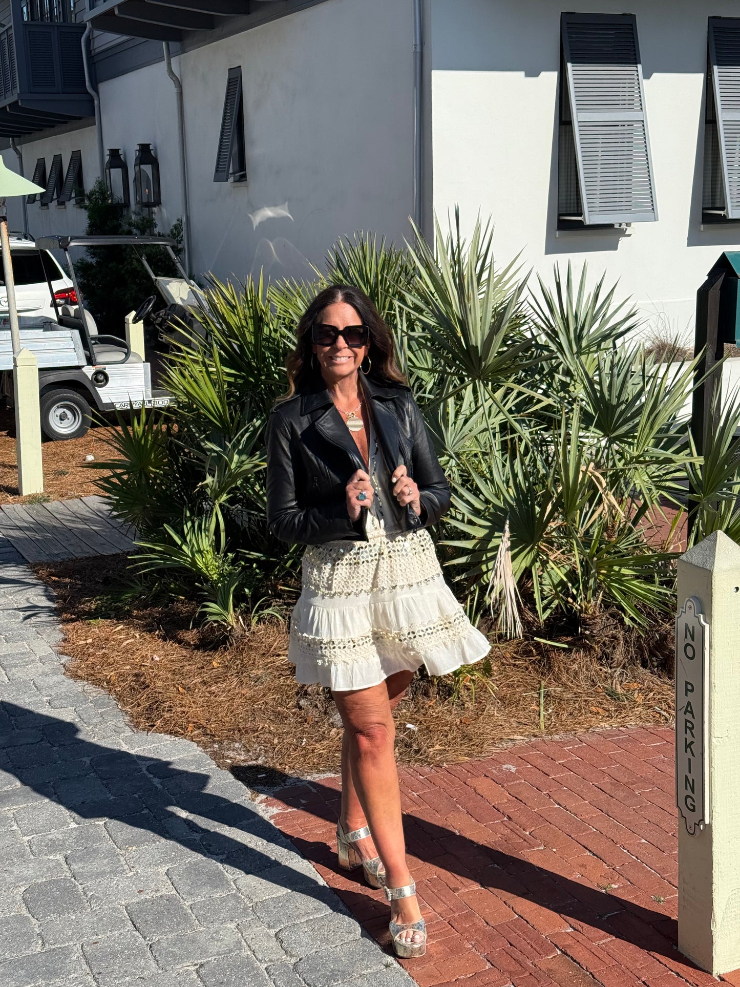 woman in cream and gold dress modeling wearing black cropped leather jacket