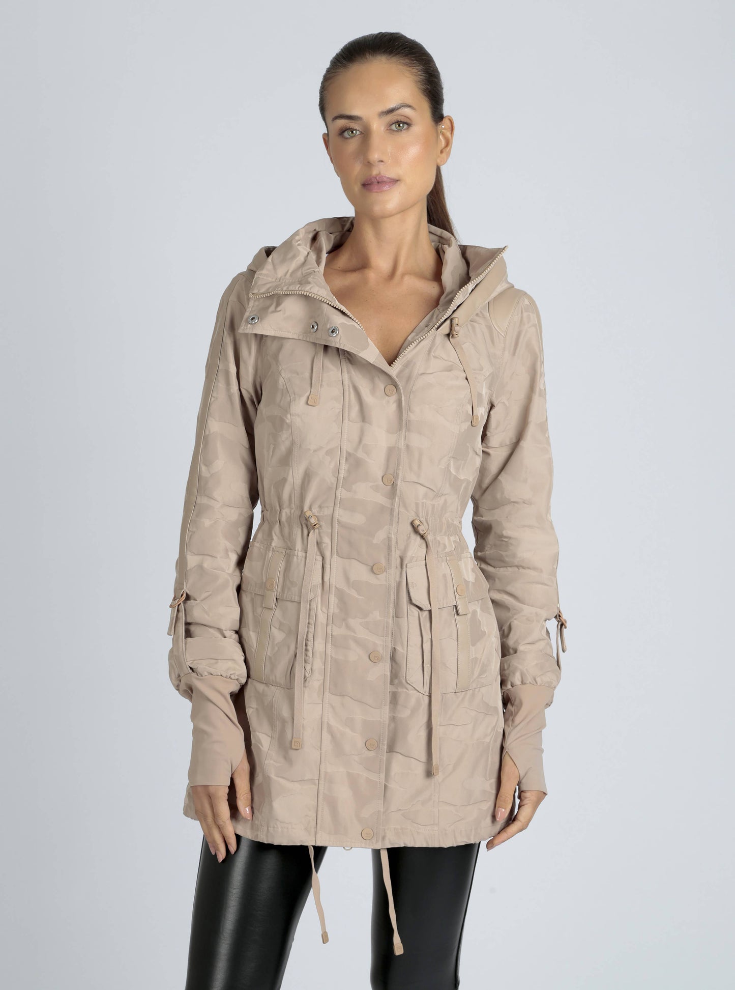 Woman wearing a beige hooded jacket on a light gray background
