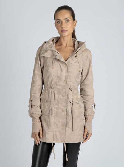 Woman wearing a beige hooded jacket on a light gray background