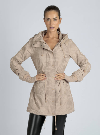 Woman wearing a beige hooded jacket on a gray background