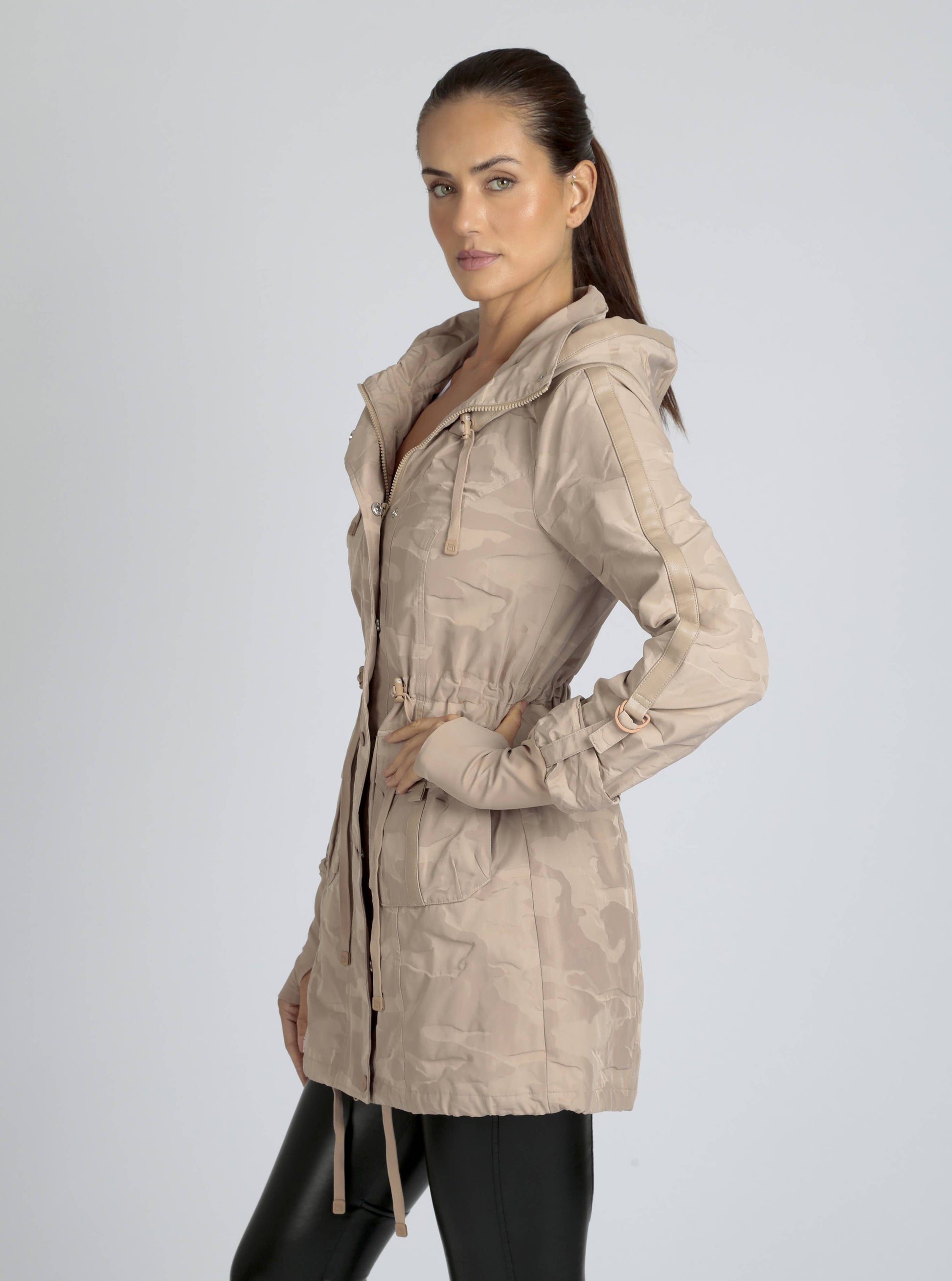Woman wearing a beige hooded jacket on a light gray background