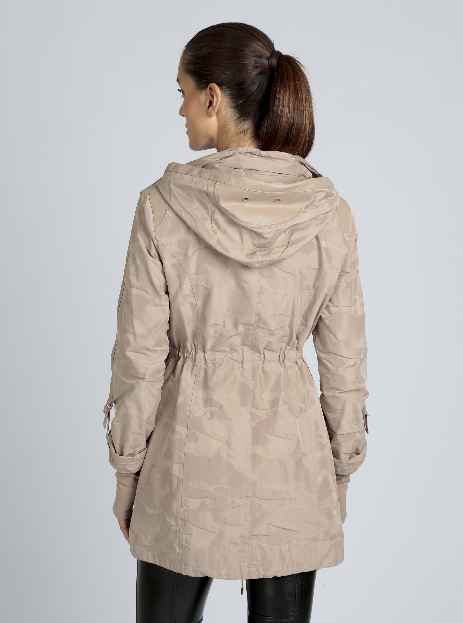 Woman wearing a beige hooded coat on a plain background