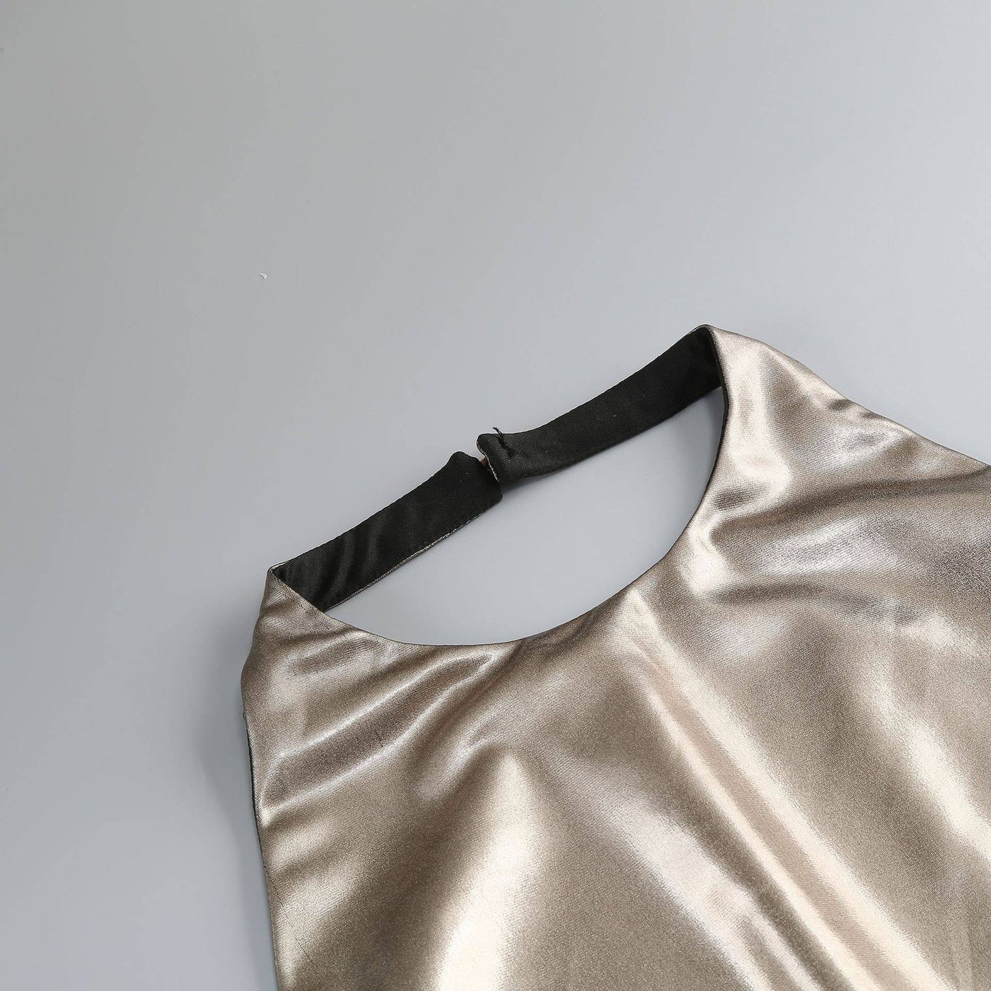 Gold metallic dress with black strap on a light gray background