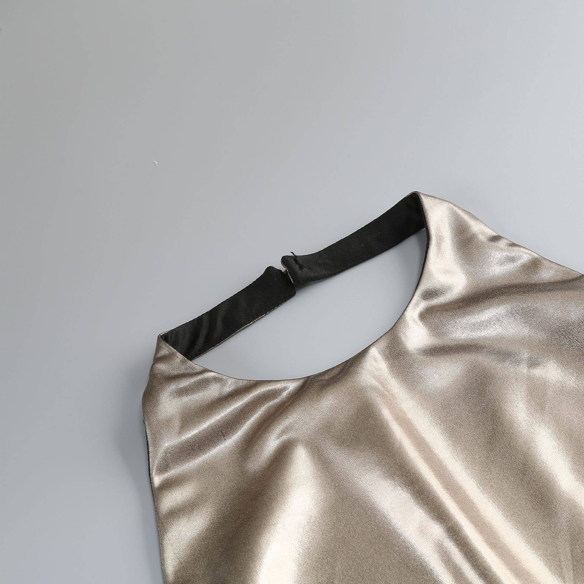 Gold metallic dress with black strap on a light gray background