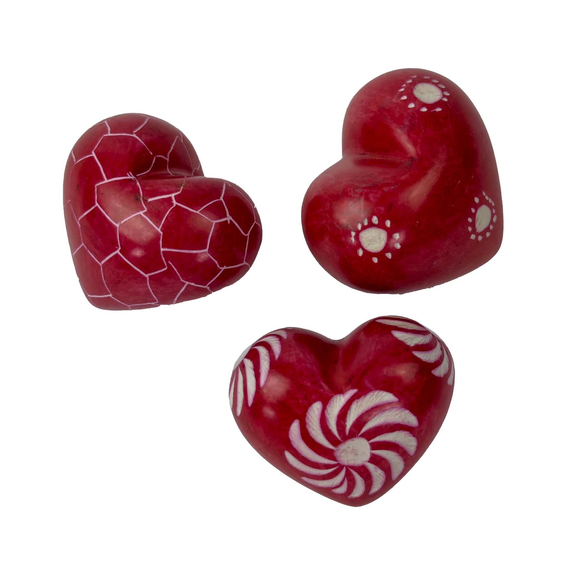 Three red heart-shaped candies with white patterns on a white background