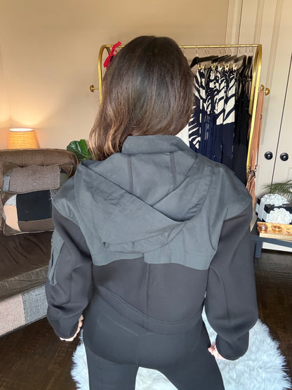 Person wearing a gray coat in a room with furniture and decor.