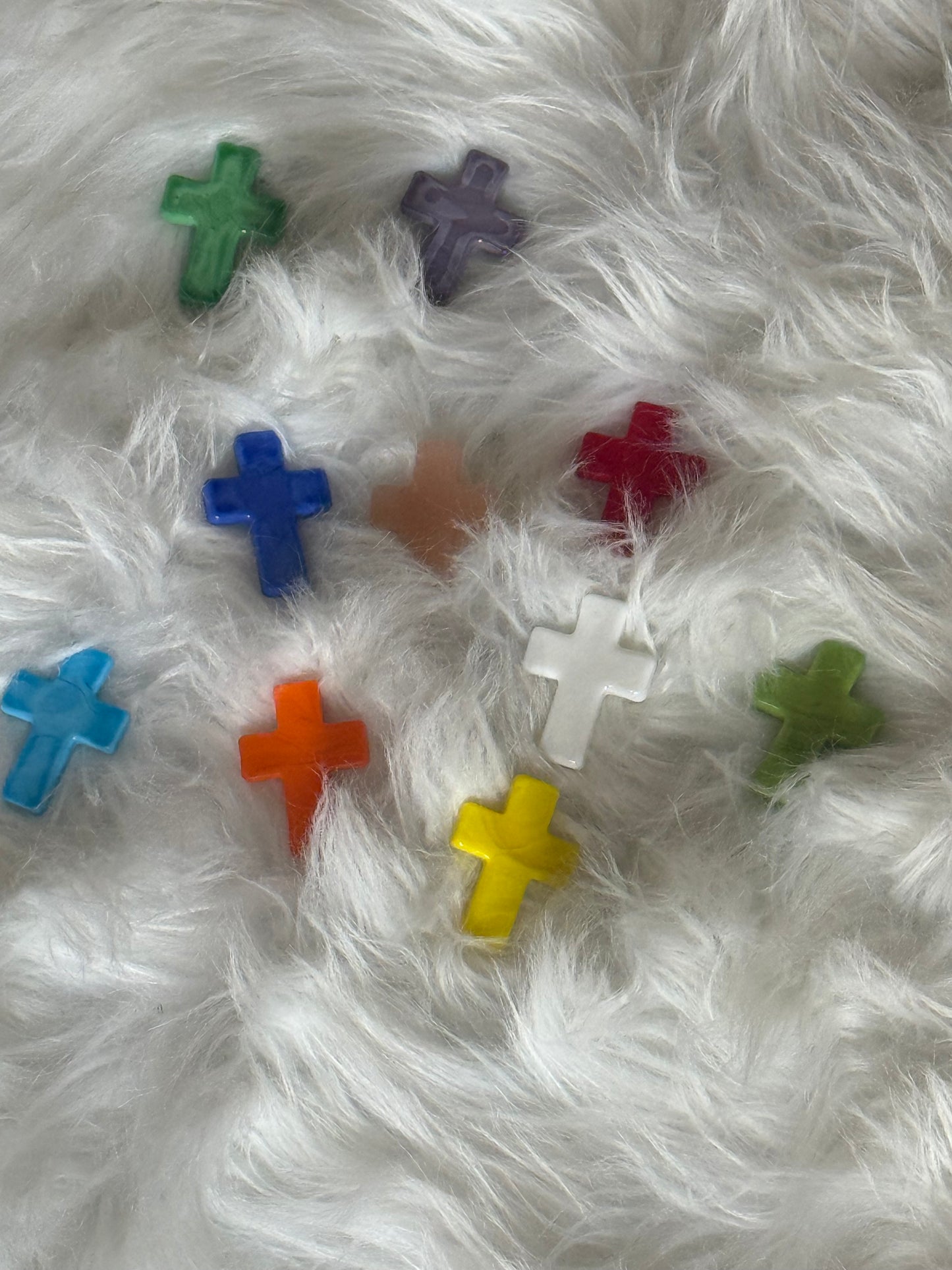 Colorful glass crosses on a white fluffy surface.