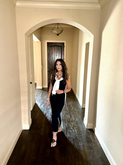 Woman standing in a hallway wearing a black and white outfit.