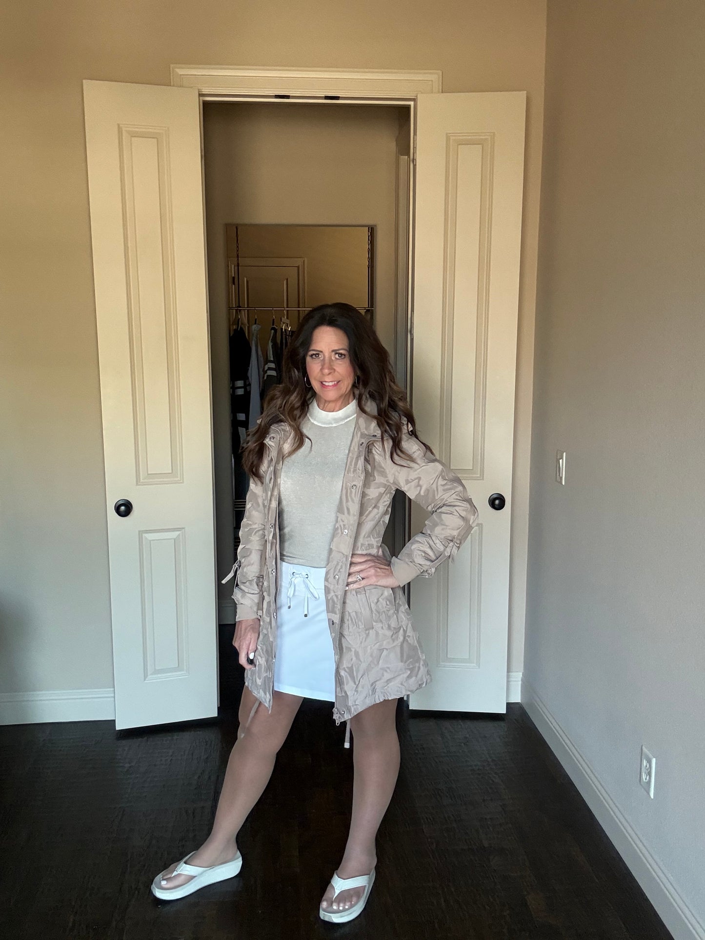Woman standing in a room with beige walls and white doors.