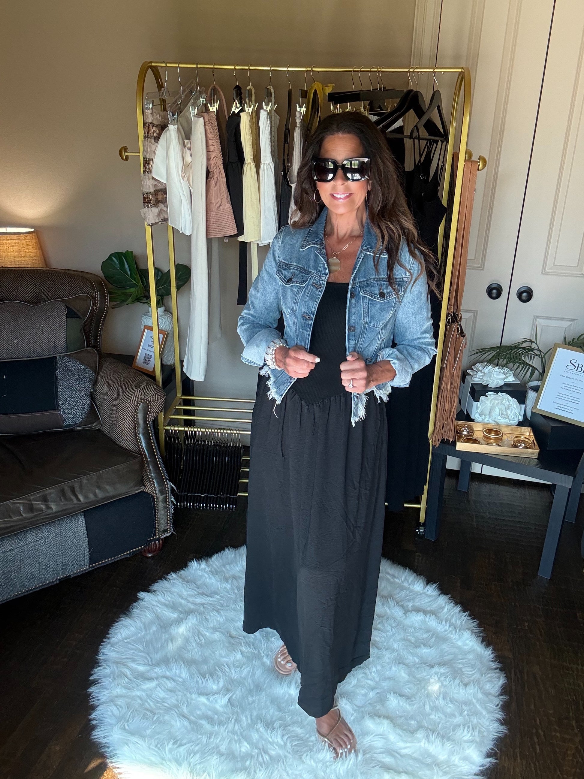 Woman standing in a room with a clothing rack and sofa.