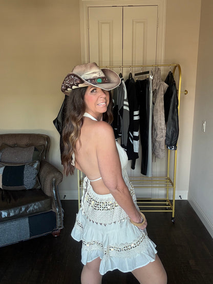 Woman modeling an ivory and gold halter dress and a cowboy hat in a boutique.