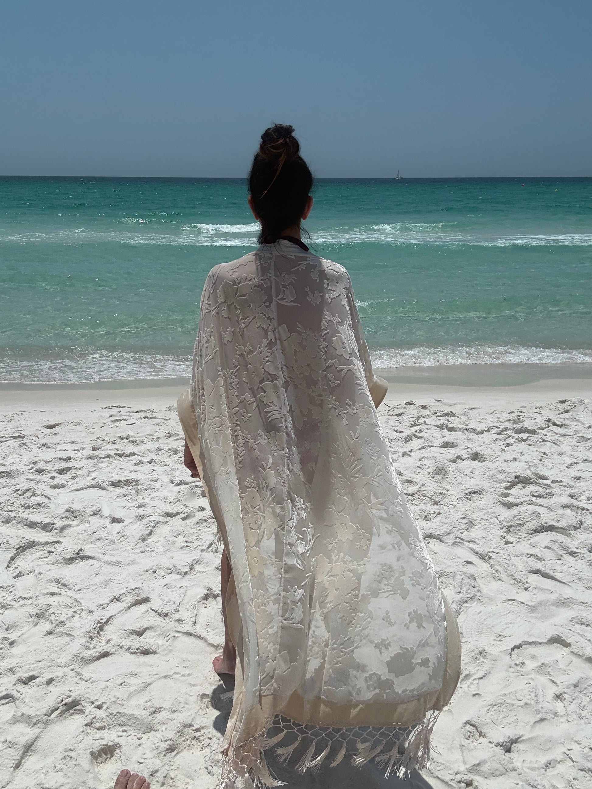 ivory kimono worn by womAN ON BEACH WIOTH OCEAN BACKGROUND