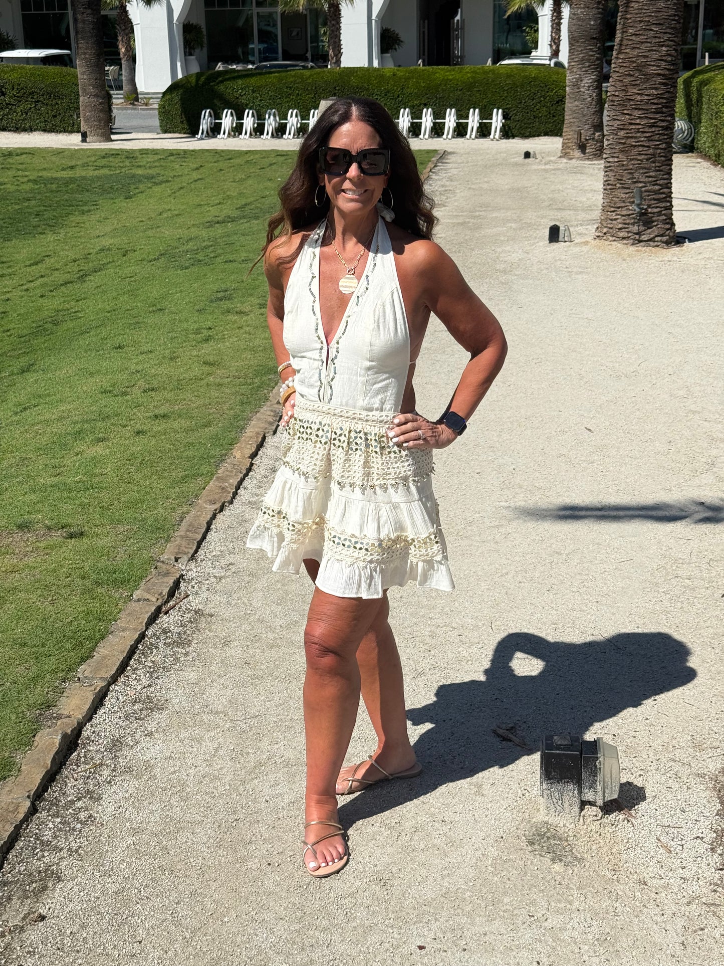 woman posing wearing cream and gold halter dress