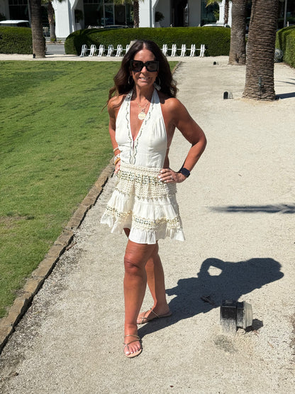 woman posing wearing cream and gold halter dress