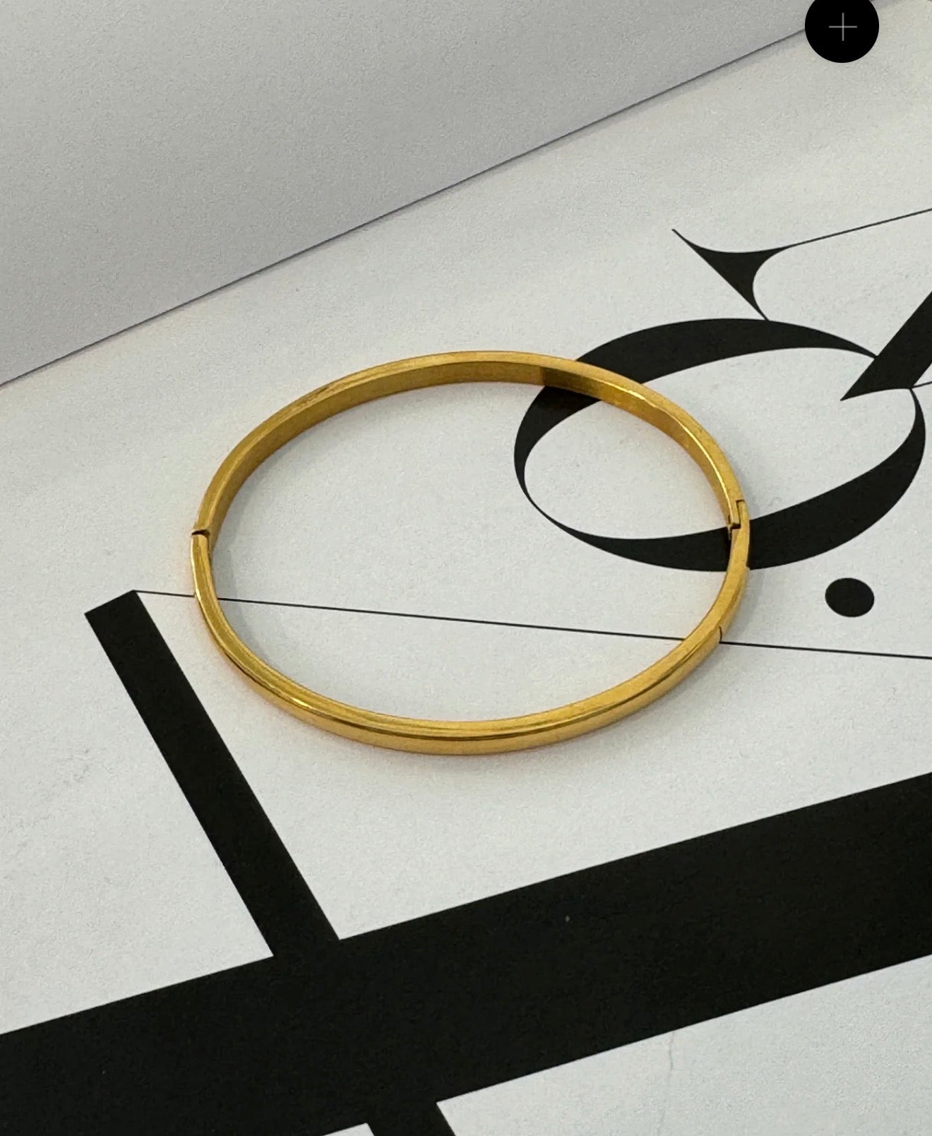 thin gold bracelet on a black and white table