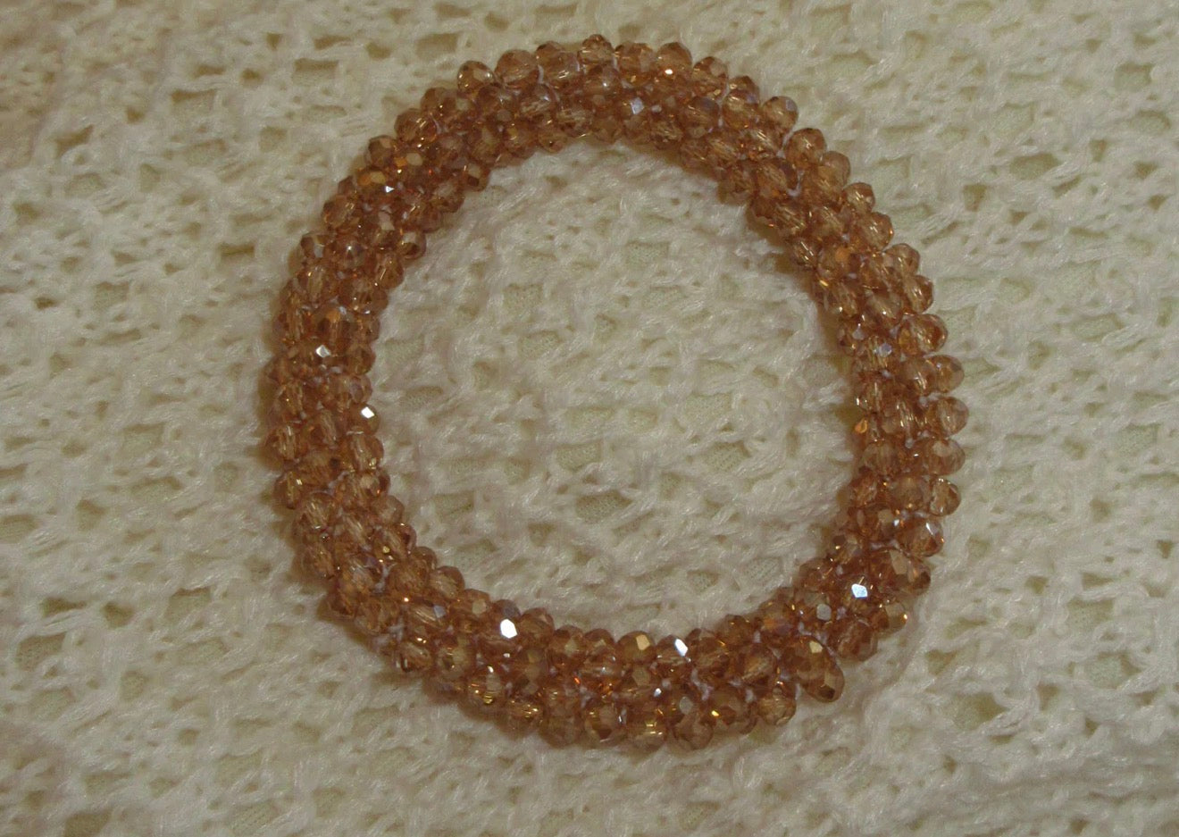 Brown beaded bracelet on a textured beige surface