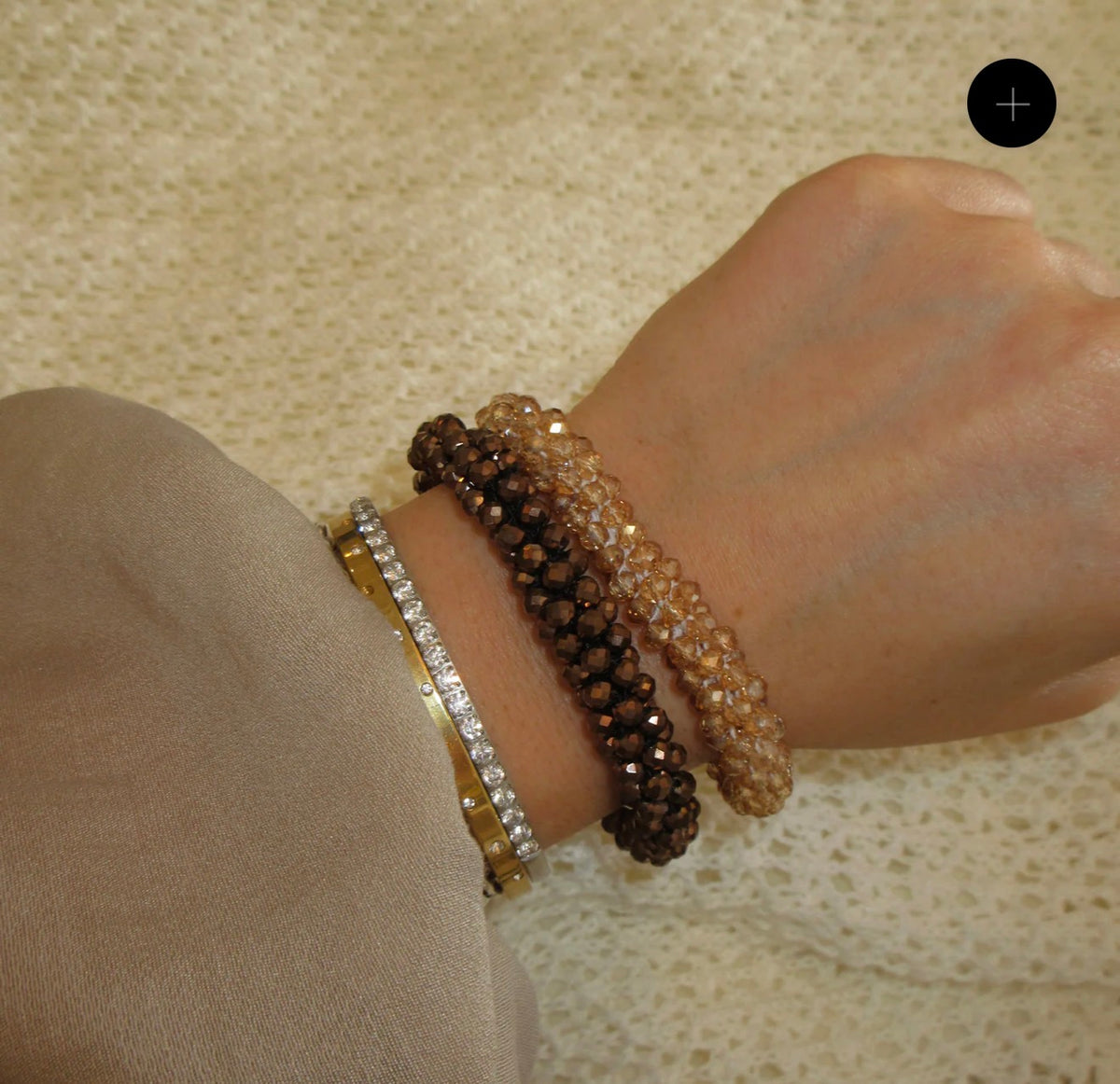a woman's wrist wearing four different beaded bracelets amber, brown, diamond, gold