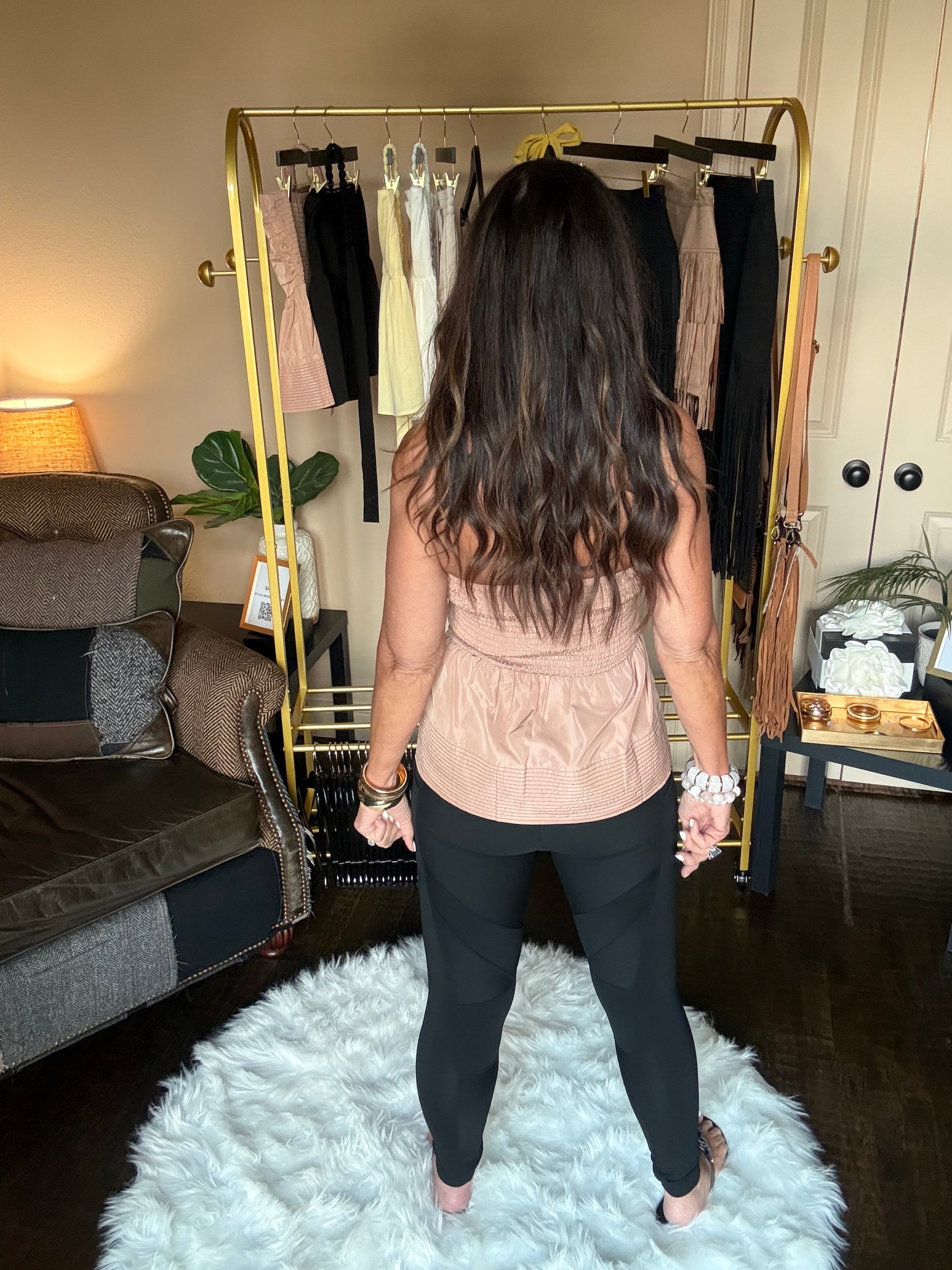 Person standing in a room with a white rug, furniture, and decorative items.