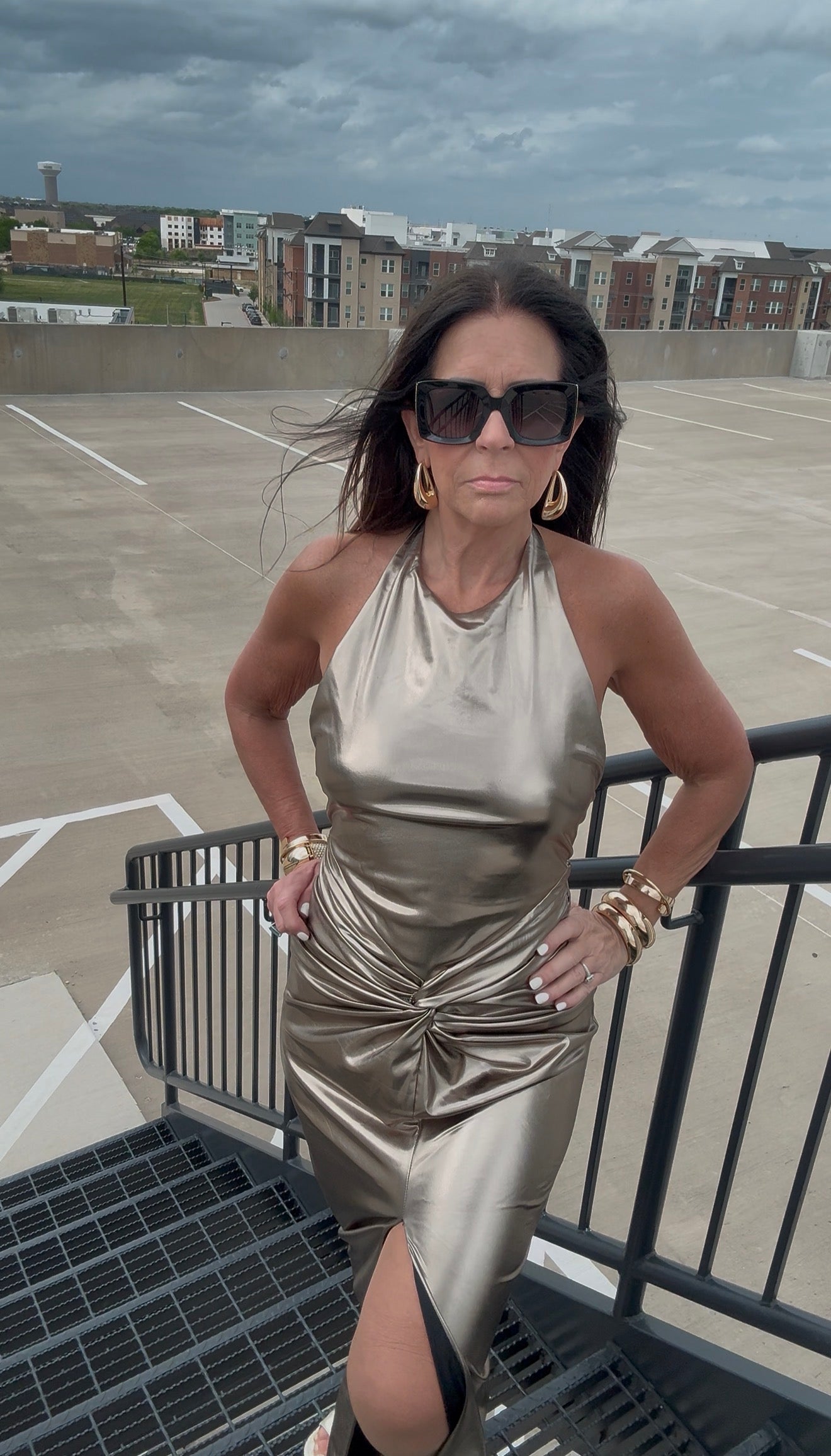 Woman in a metallic dress standing on a rooftop with a cityscape background
