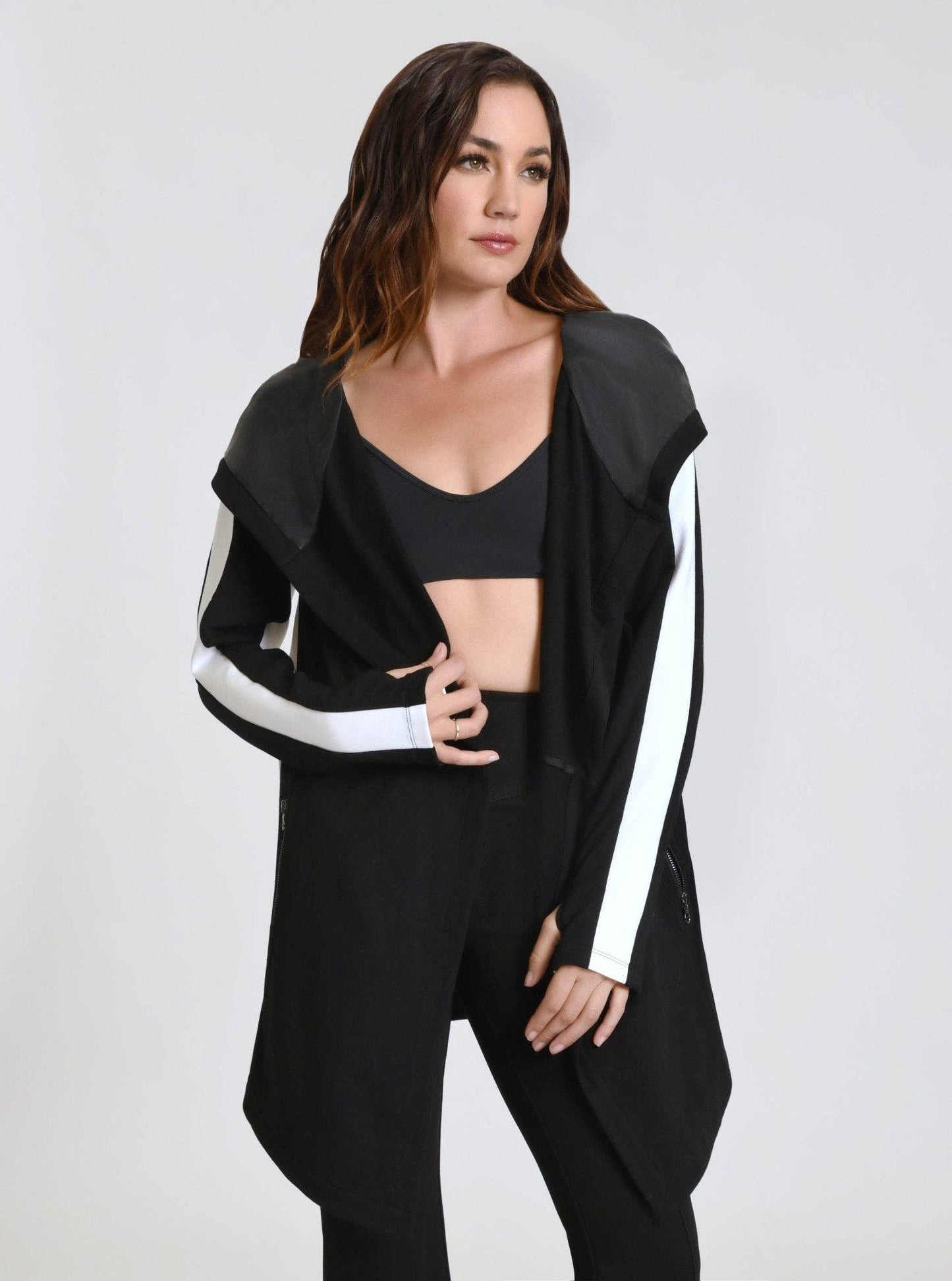 Woman wearing a black outfit with white accents on a plain background