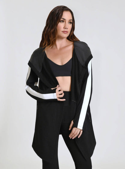 Woman wearing a black outfit with white accents on a plain background