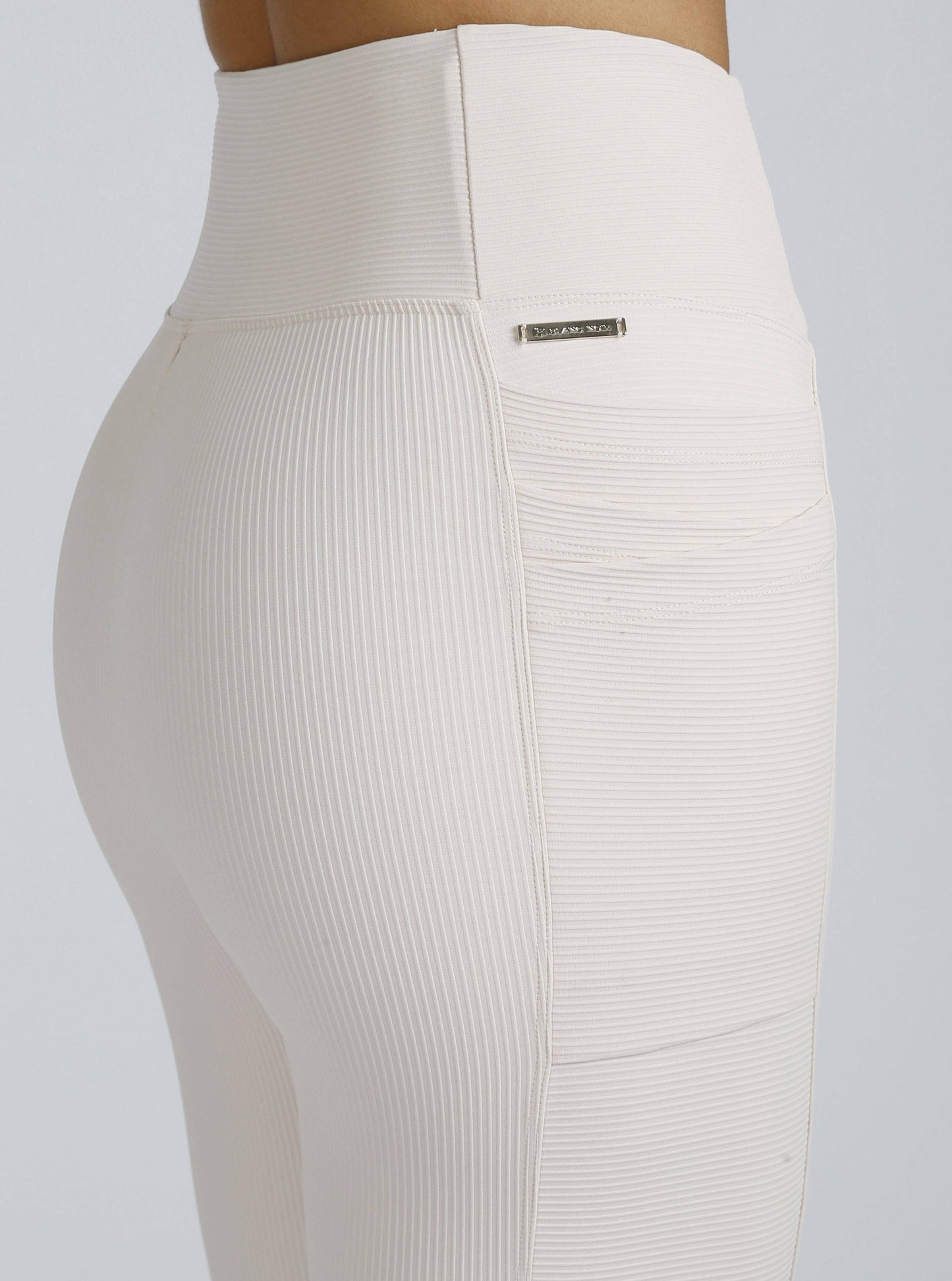 Beige leggings with a brand label on a light gray background
