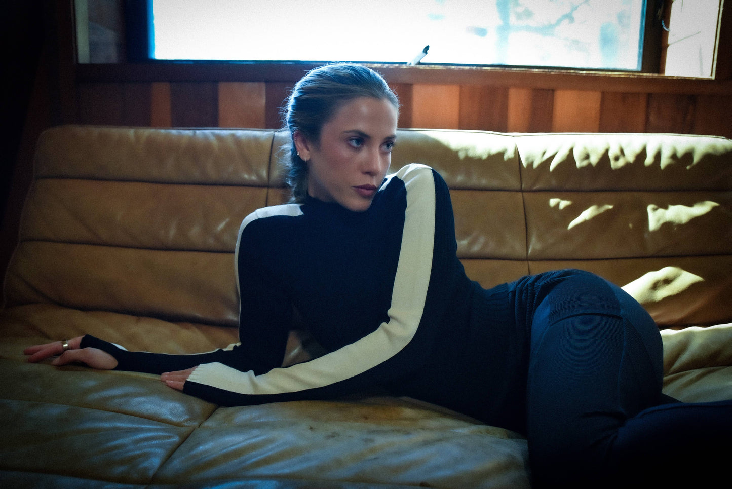 Person wearing a black and white outfit sitting on a leather couch.