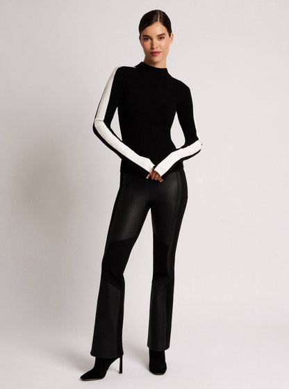 Person wearing a black and white outfit on a plain background