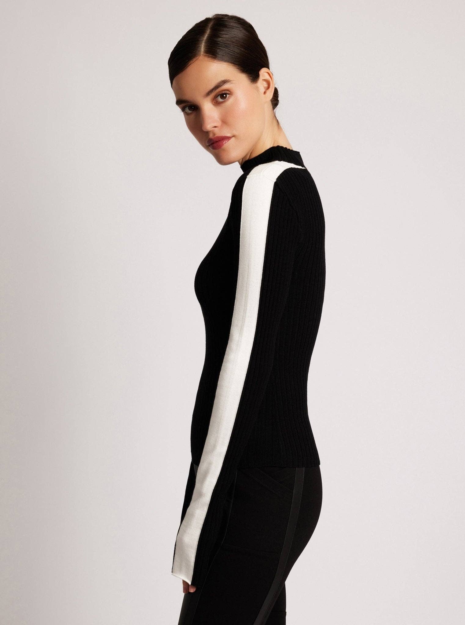 Woman wearing a black outfit with a white stripe on a light gray background