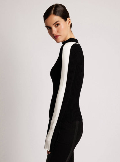 Woman wearing a black outfit with a white stripe on a light gray background