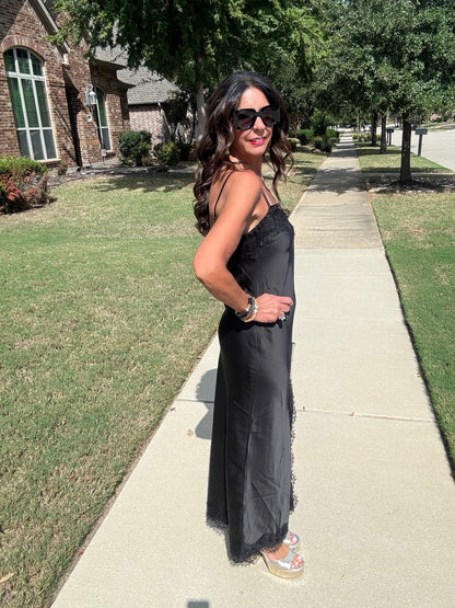 Side view of black satin lace trim slip maxi dress showing the draped silhouette and lace hem.