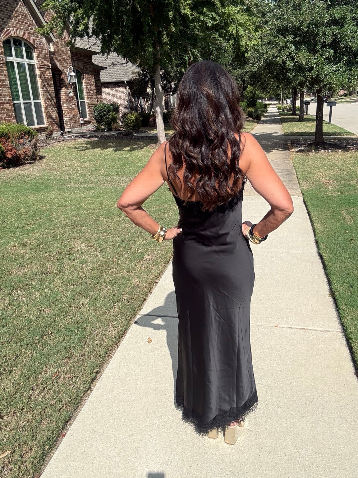 Back view of black satin slip maxi dress showing slim shoulder straps and full-length silhouette.