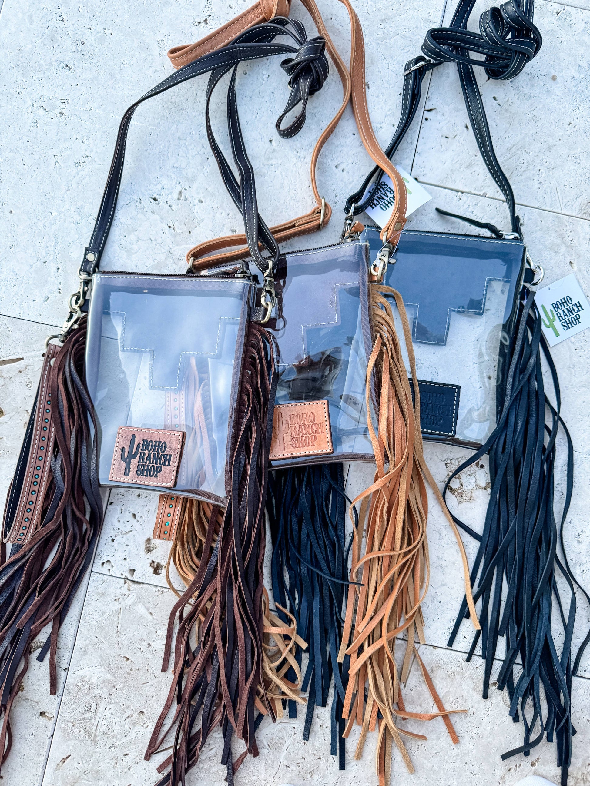 Three clear bags with fringe straps on a light surface