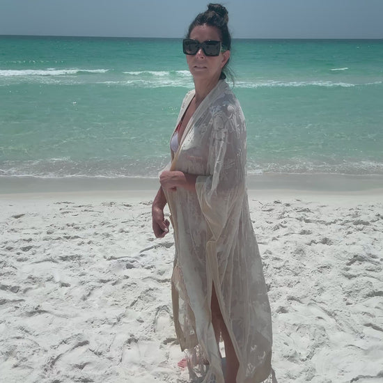 ivory kimono worn by womAN ON BEACH WIOTH OCEAN BACKGROUND
